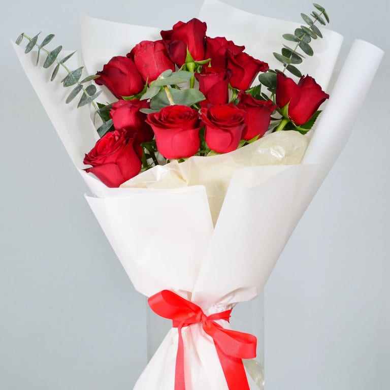Red roses wrapped in white paper with a red ribbon
