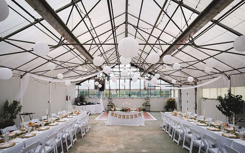 Lantern-lit tables set for a reception in the greenhouse